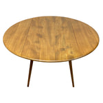 Load image into Gallery viewer, A round wooden dining table with a warm golden-brown finish and three tapered legs, shown from a high angle on a white background.
