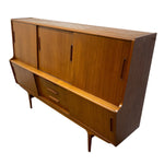 Load image into Gallery viewer, Mid-century modern wooden sideboard cabinet with a warm honey finish, featuring three upper doors with vertical handles, two lower drawers with horizontal pulls, and tapered legs, shown on a plain white background.
