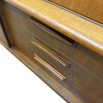 Load image into Gallery viewer, Close-up of a wooden furniture piece showing drawers with curved metal handles and a polished wood grain finish.
