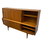 Load image into Gallery viewer, Mid-century modern wooden sideboard cabinet with a warm walnut finish, featuring two upper doors, two lower doors, open shelving, and tapered legs, shown on a plain white background.
