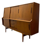 Load image into Gallery viewer, Mid-century modern wooden credenza or sideboard cabinet with a warm medium-brown wood grain finish, featuring three upper doors with vertical handles, three drawers in the center with horizontal handles, and two lower cabinet sections with vertical handles, supported by angled legs.
