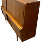 Load image into Gallery viewer, Mid-century modern wooden sideboard cabinet with warm medium-brown wood grain, featuring two cabinet doors, a lower drawer, and open shelving, shown on a plain white background.
