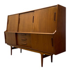 Load image into Gallery viewer, Mid-century modern wooden writing desk with a warm walnut finish, featuring three upper cabinet doors, three drawers in the center, and lower cabinet doors, shown on a plain white background.

