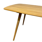 Load image into Gallery viewer, A close-up of a mid-century modern wooden dining table showing the rounded rectangular tabletop and angled splayed legs, crafted from light natural wood with a glossy finish.
