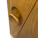 Load image into Gallery viewer, Close-up of a round wooden cabinet knob mounted on a matching wood cabinet door, showing the natural oak grain and warm golden-brown finish against a white background.
