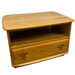 Load image into Gallery viewer, A mid-century modern wooden side table or low cabinet with a single drawer, featuring a warm honey-wood finish and rounded edges, shown against a plain white background.
