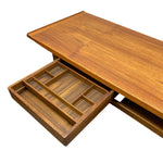 Load image into Gallery viewer, A mid-century modern wooden desk or console table with a warm brown wood grain finish, featuring a pull-out organizer drawer shown in the foreground on a white background.
