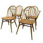 Load image into Gallery viewer, Four wooden spindle-back dining chairs with a warm medium-brown finish, arranged on a plain white background.
