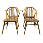 Load image into Gallery viewer, Four wooden dining chairs with spindle-back designs and curved armrests, shown on a plain white background.
