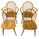 Load image into Gallery viewer, Four wooden dining chairs with spindle backs and curved armrests, arranged in two pairs on a plain white background.

