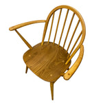 Load image into Gallery viewer, A mid-century modern wooden armchair with a curved backrest, spindle back, and integrated armrests, shown from an elevated angle on a white background.
