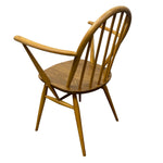 Load image into Gallery viewer, A mid-century modern wooden armchair with a curved backrest, spindle back design, and angled legs, shown from a three-quarters perspective on a white background.
