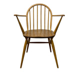 Load image into Gallery viewer, A mid-century modern wooden armchair with a spindle back, angled legs, and a curved armrest, shown against a plain white background.
