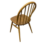 Load image into Gallery viewer, A mid-century modern wooden dining chair with a curved spindle back, round seat, and tapered legs, shown from a three-quarters angle on a white background.
