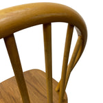 Load image into Gallery viewer, Close-up of a wooden spindle-back chair showing the curved backrest, vertical spindles, and part of the wooden seat against a plain white background.
