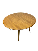 Load image into Gallery viewer, A round wooden dining table with a warm medium-brown finish and four tapered legs, shown on a plain white background.
