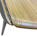 Load image into Gallery viewer, Close-up detail of a mid-century modern wooden table corner, showing a curved wood grain top, dark metal hinge, and tapered metal leg against a white background.
