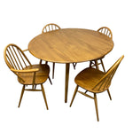 Load image into Gallery viewer, A mid-century modern wooden dining set consisting of a round table and four spindle-back chairs, shown against a plain white background.
