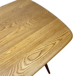 Load image into Gallery viewer, Close-up of a light brown wooden table top with rounded corners and visible wood grain, with a small dark metal leg visible against a white background.
