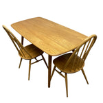 Load image into Gallery viewer, A mid-century modern wooden dining table with two matching spindle-back chairs, shown on a plain white background.
