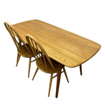Load image into Gallery viewer, A light oak wood dining table with rounded corners and two matching spindle-back chairs, shown on a plain white background.
