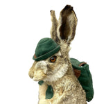 Load image into Gallery viewer, A taxidermy-style rabbit wearing a small green felt hat and matching green felt backpack, photographed against a plain white background.
