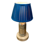 Load image into Gallery viewer, A decorative table lamp featuring a blue pleated fabric shade, a vintage metal Absinthe Vodka bottle as the base, and a round light wood pedestal.
