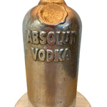 Load image into Gallery viewer, A vintage Absolut Vodka metal bottle sculpture or decorative piece, featuring embossed lettering on a textured, metallic bronze and gold-toned surface, shown against a plain white background.
