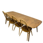 Load image into Gallery viewer, A mid-century modern wooden dining table with four matching spindle-back chairs, shown on a plain white background.
