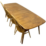 Load image into Gallery viewer, A mid-century modern wooden dining table with matching spindle-back chairs, shown from an elevated angle against a plain white background.

