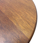 Load image into Gallery viewer, Close-up of a round wooden tabletop showing the warm medium-brown wood grain and a rounded edge against a white background.
