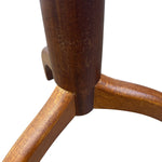Load image into Gallery viewer, Close-up detail of a wooden chair or stool leg joint, showing a dark brown cylindrical pedestal base meeting three angled wooden legs with visible wood grain and finish on a white background.
