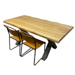 Load image into Gallery viewer, A live-edge wood dining table with a natural oak top and dark metal A-frame legs, accompanied by two matching wooden chairs with black metal frames, shown on a plain white background.
