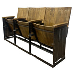 Load image into Gallery viewer, A set of four rustic wooden auditorium theater seats with dark metal frames, shown from a three-quarters angle on a white background.
