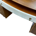 Load image into Gallery viewer, Close-up of a mid-century modern desk featuring a curved wood top, a light gray painted drawer front, and brass drawer pulls against a white background.
