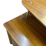 Load image into Gallery viewer, Close-up of a wooden table corner showing a warm brown wood grain finish, a brass-colored leg, and part of a white background.
