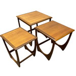 Load image into Gallery viewer, Three nested wooden nesting tables with a warm medium-brown wood grain finish and sculptural curved legs, shown on a plain white background.
