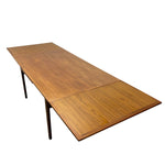 Load image into Gallery viewer, A mid-century modern extendable dining table made of warm medium-brown wood with dark metal legs, shown on a plain white background.
