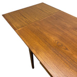 Load image into Gallery viewer, A close-up of a wooden dining table top with a warm medium-brown walnut finish, showing the grain pattern and a visible leg against a plain white background.
