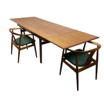 Load image into Gallery viewer, A mid-century modern wooden dining table with two matching chairs featuring green upholstered seats, shown on a solid white background.
