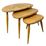 Load image into Gallery viewer, Three nested oval nesting tables in a warm medium brown wood finish with tapered legs, shown on a plain white background.
