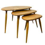 Load image into Gallery viewer, Three nested oval nesting tables made of light brown wood with tapered legs, shown on a plain white background.
