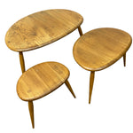 Load image into Gallery viewer, Three mid-century modern wooden nesting tables in oval shapes with tapered legs, shown on a plain white background.
