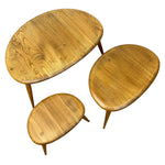 Load image into Gallery viewer, Three-piece mid-century modern wooden nesting coffee table set with oval wood-grain tops and tapered wooden legs, shown on a plain white background.
