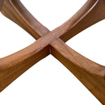 Load image into Gallery viewer, Close-up of a wooden table base with four curved legs crossing in an X shape, showing a warm medium-brown wood grain on a white background.
