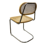 Load image into Gallery viewer, A modern cantilever dining chair with a light natural wood seat and backrest, a woven cane backrest panel, and a polished chrome tubular metal frame, shown on a plain white background.
