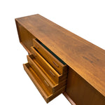 Load image into Gallery viewer, A mid-century modern wooden sideboard or credenza with a warm medium-brown wood finish, featuring three open drawers showing brass handles, photographed on a solid white background.
