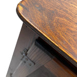 Load image into Gallery viewer, Close-up detail of a dark brown wooden table corner showing the rounded tabletop edge, wood grain, and part of the dark wood frame with metal hinges against a white background.
