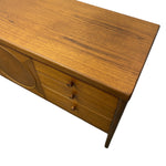 Load image into Gallery viewer, A close-up of a mid-century modern wooden sideboard or credenza, showing a warm medium-brown wood grain finish, three drawers with round knobs, and a circular inset detail on the front, set against a plain white background.
