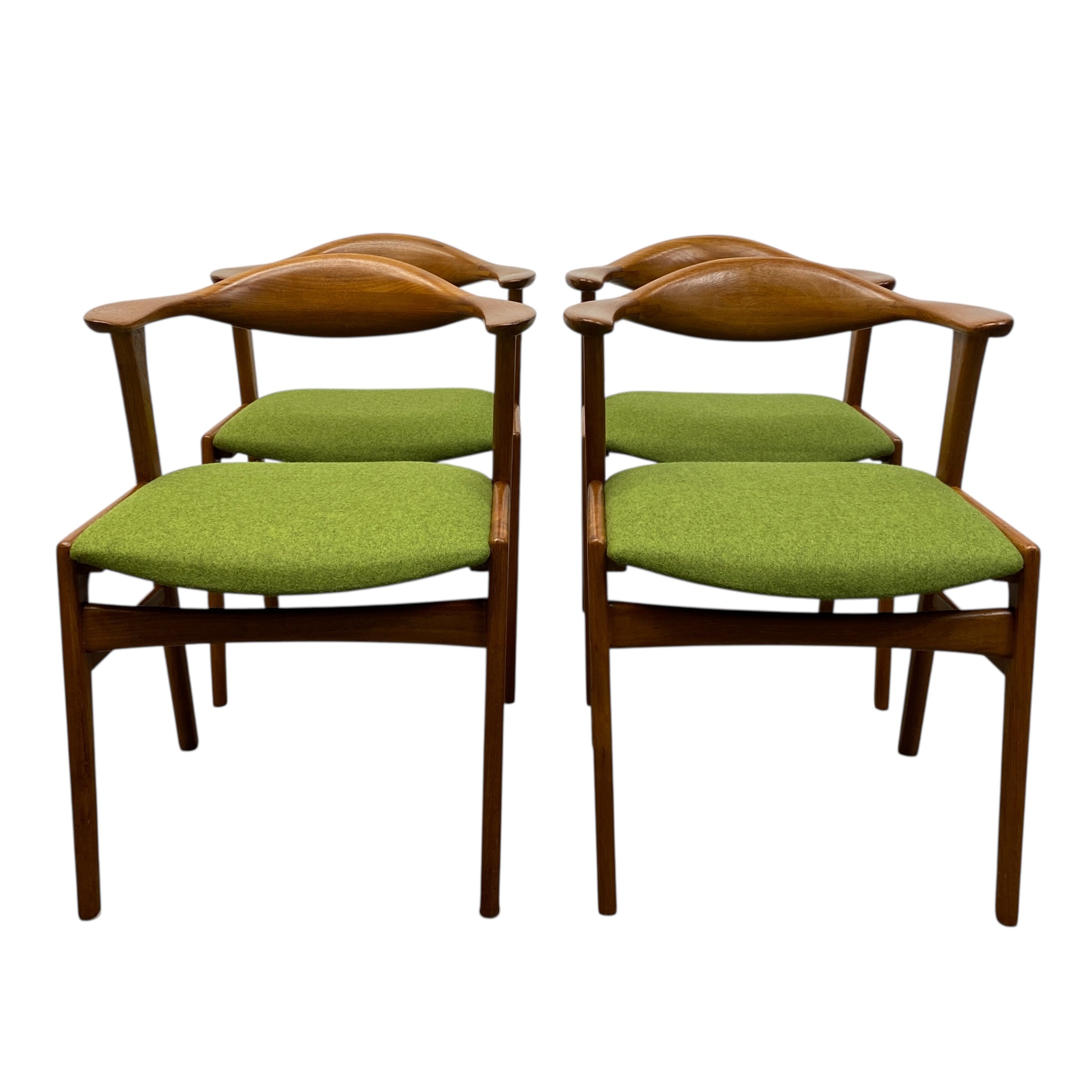 Four wooden chairs with green cushioned seats on a white background